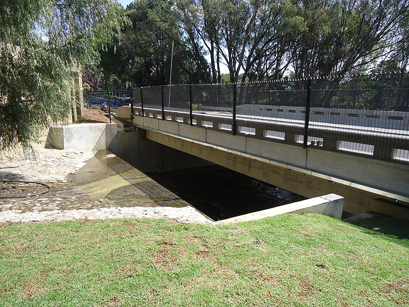 A completed reinforced concrete road bridge spanning a watercourse, representative of DNMZ structural bridge delivery